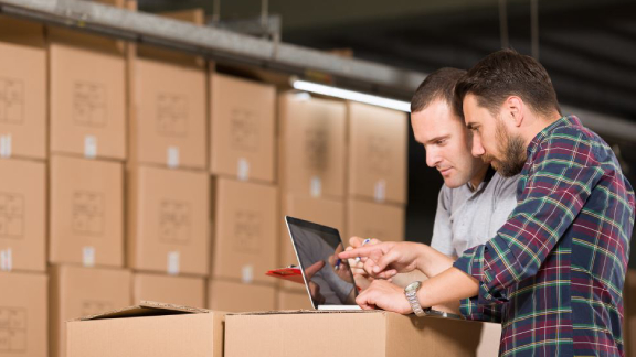 Two men in a warehouse looking at a tablet