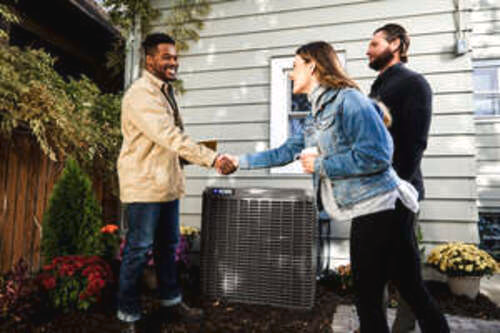 Contractor shaking hands with home owners in front of YORK heat pump